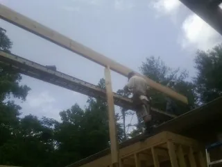 Carpenter setting a ridge beam over a new addition frame — Ice Dam Removal by Roofing Brothers in Glenford