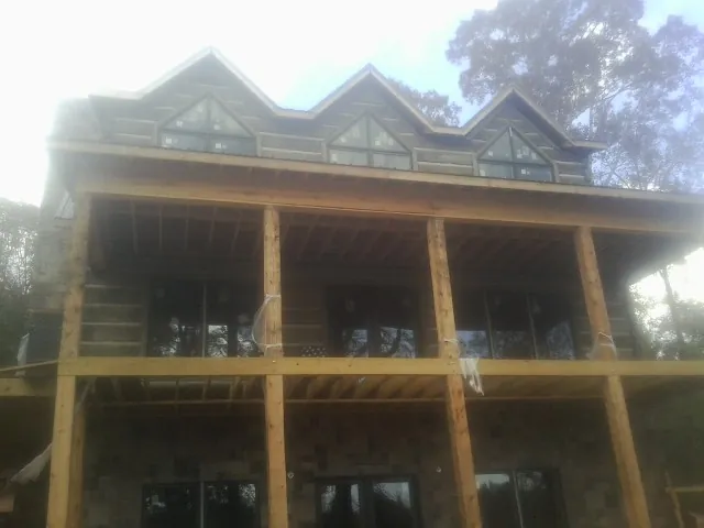 Dormers and porch framing on a large log home under construction — Roof Coating work by our crew in Glenford