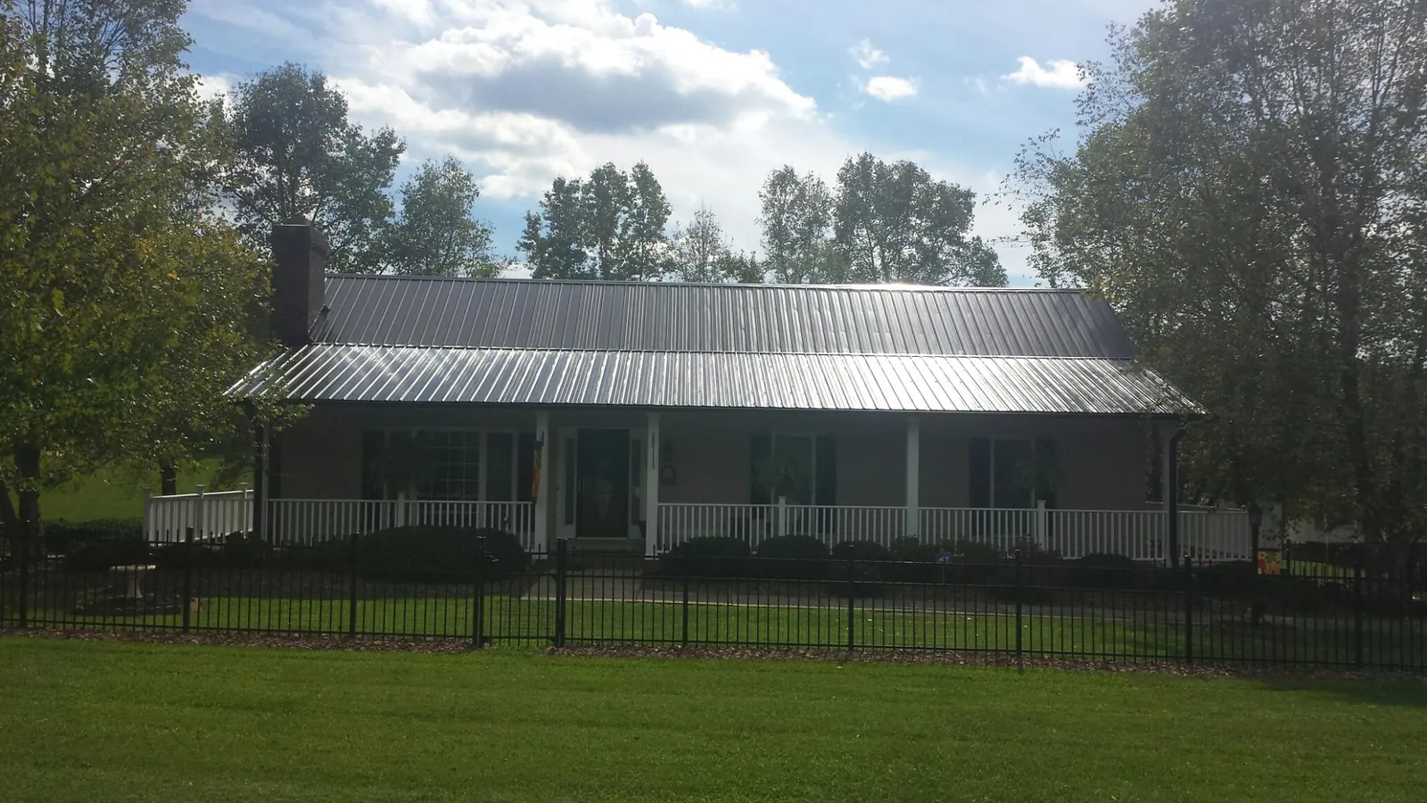 Gray metal roof on a brick ranch with a full width front porch — Gutter Guard Installation work by our crew in Glenford