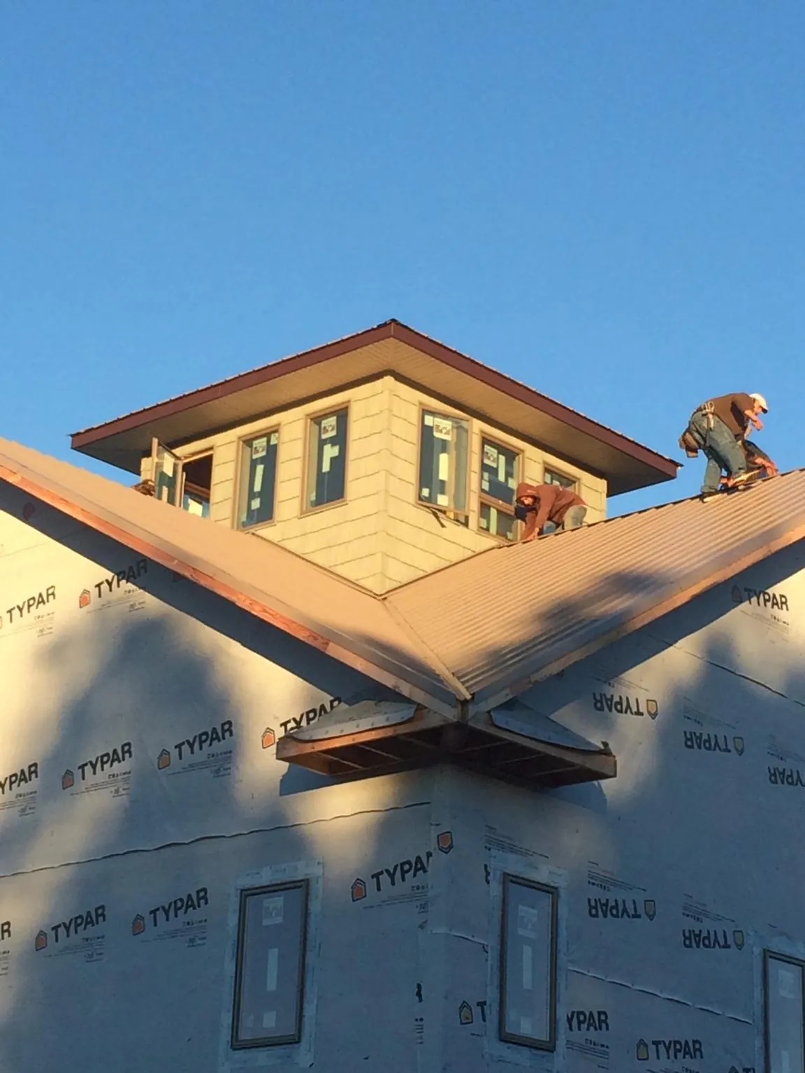 Roofers working around a rooftop cupola on a new metal roof at sunset — Roof Waterproofing in Glenford by Roofing Brothers